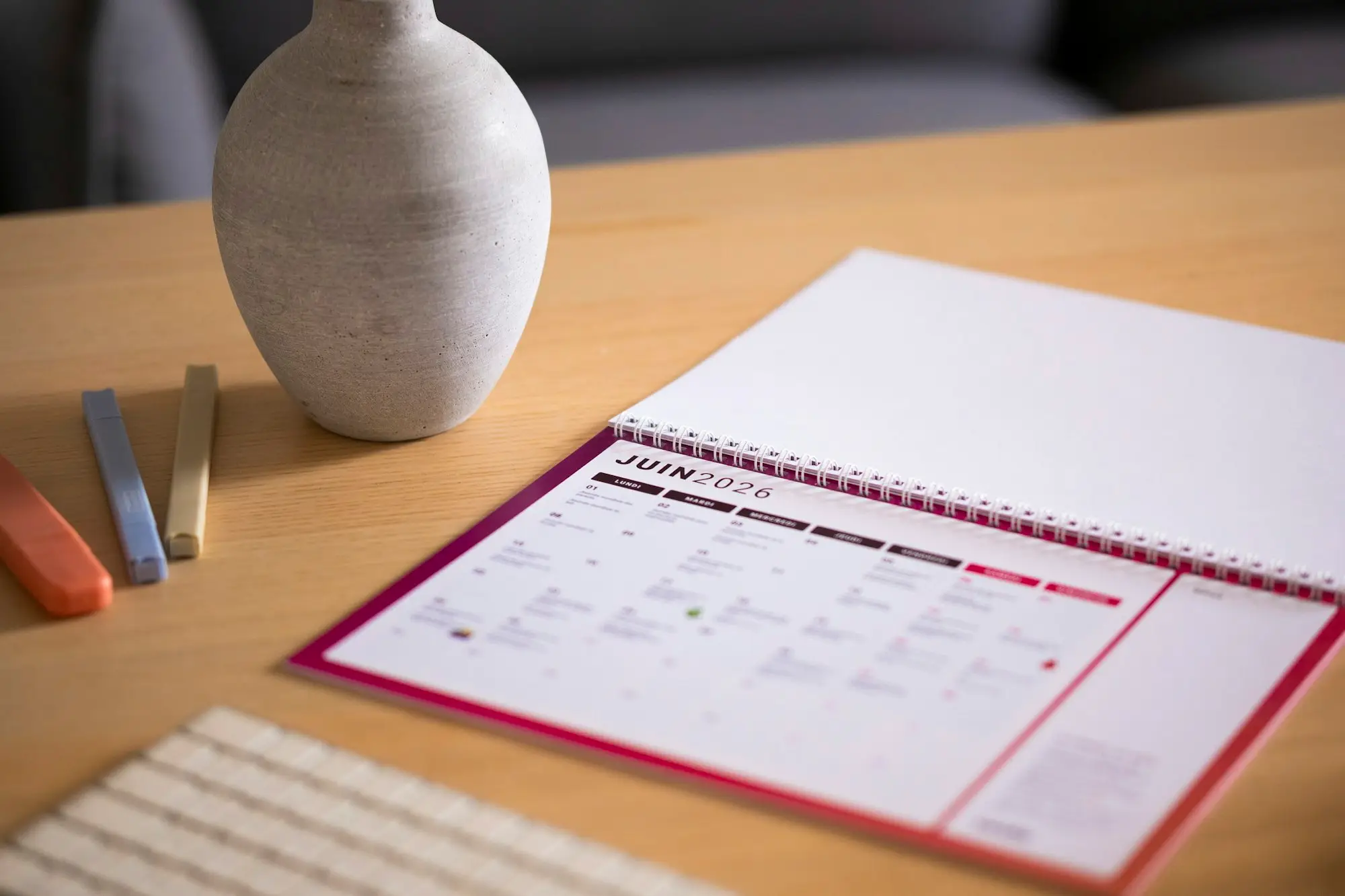 Paper calendar and a small vase on a wooden office desk