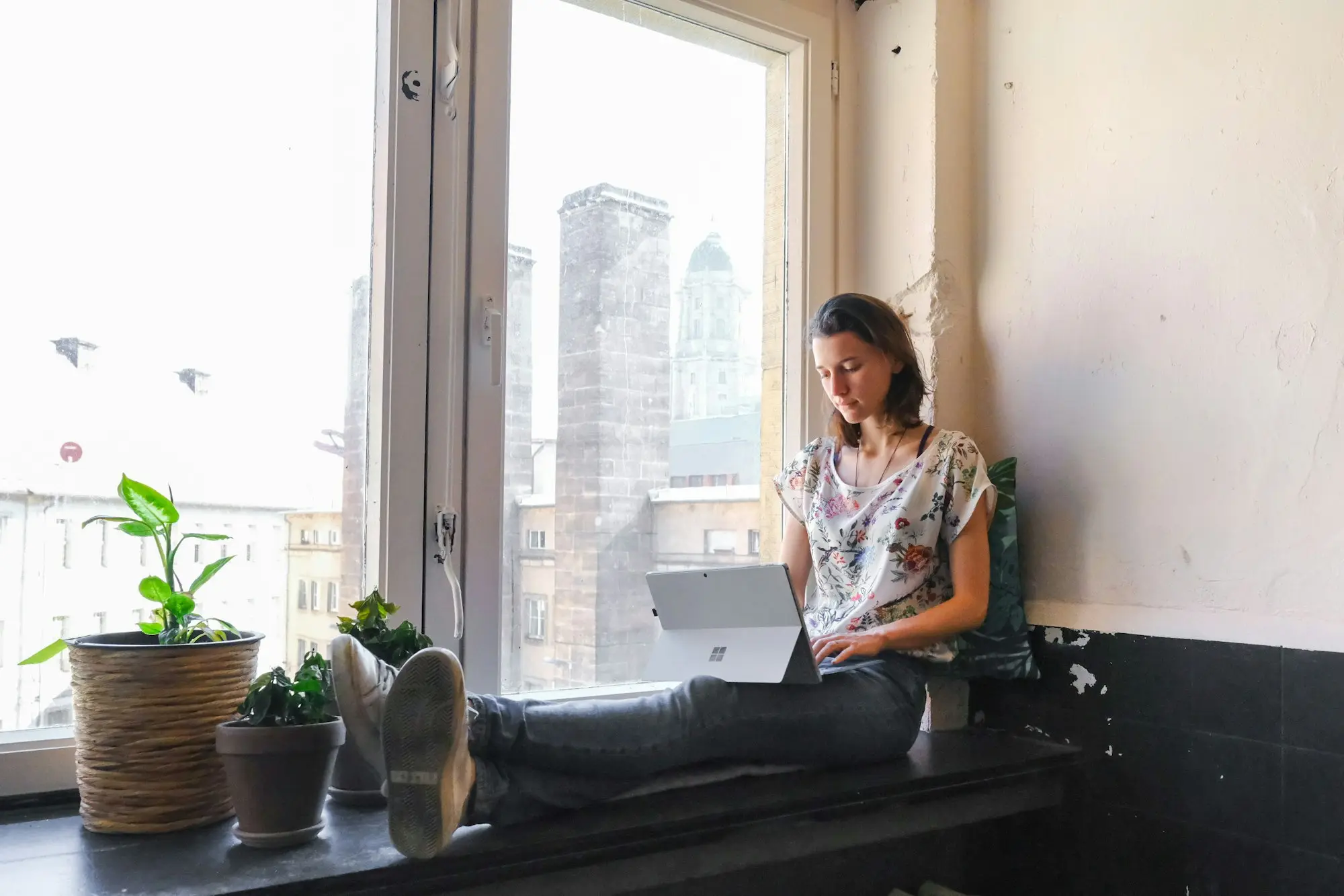 Woman sitting by a large window reading quietly