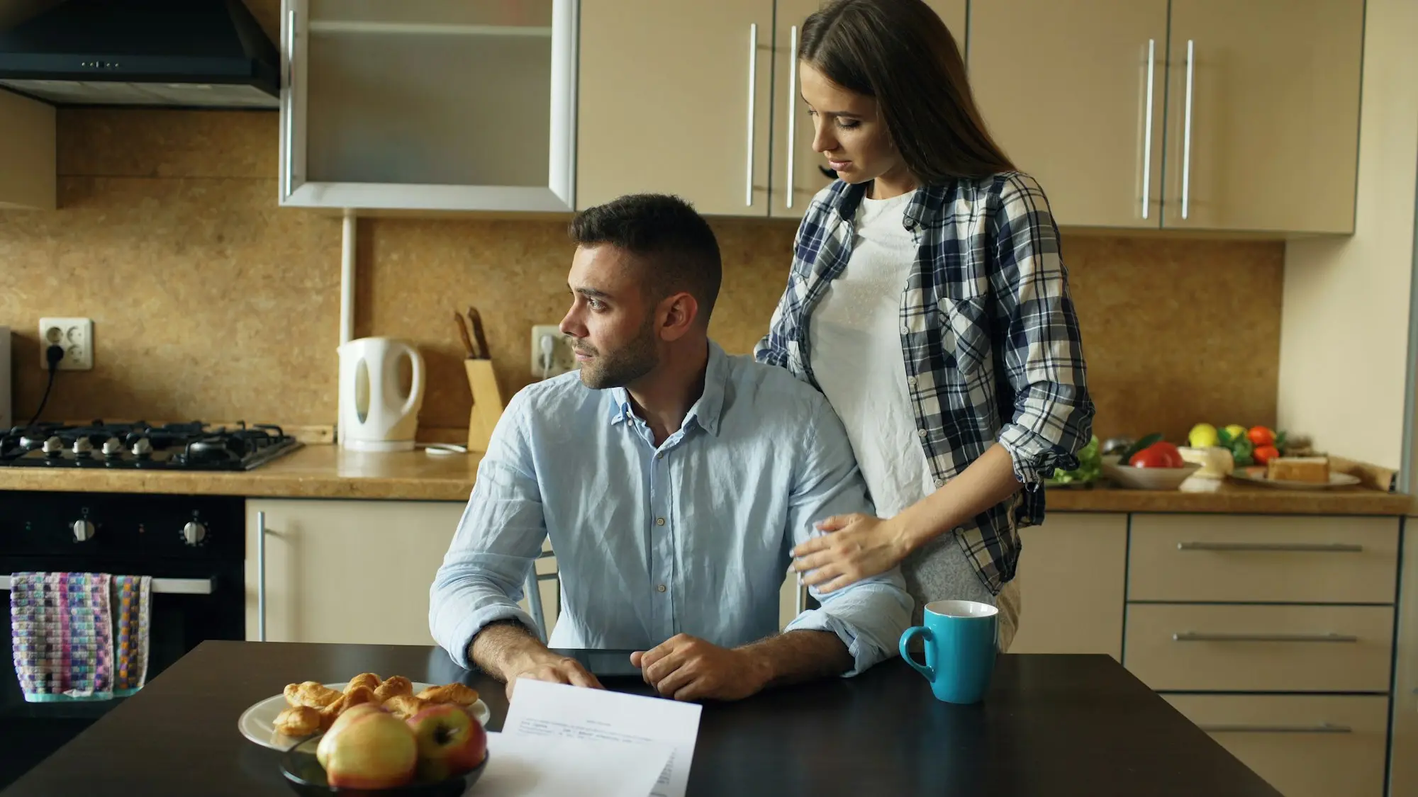 Couple sitting together at the kitchen table going over paperwork