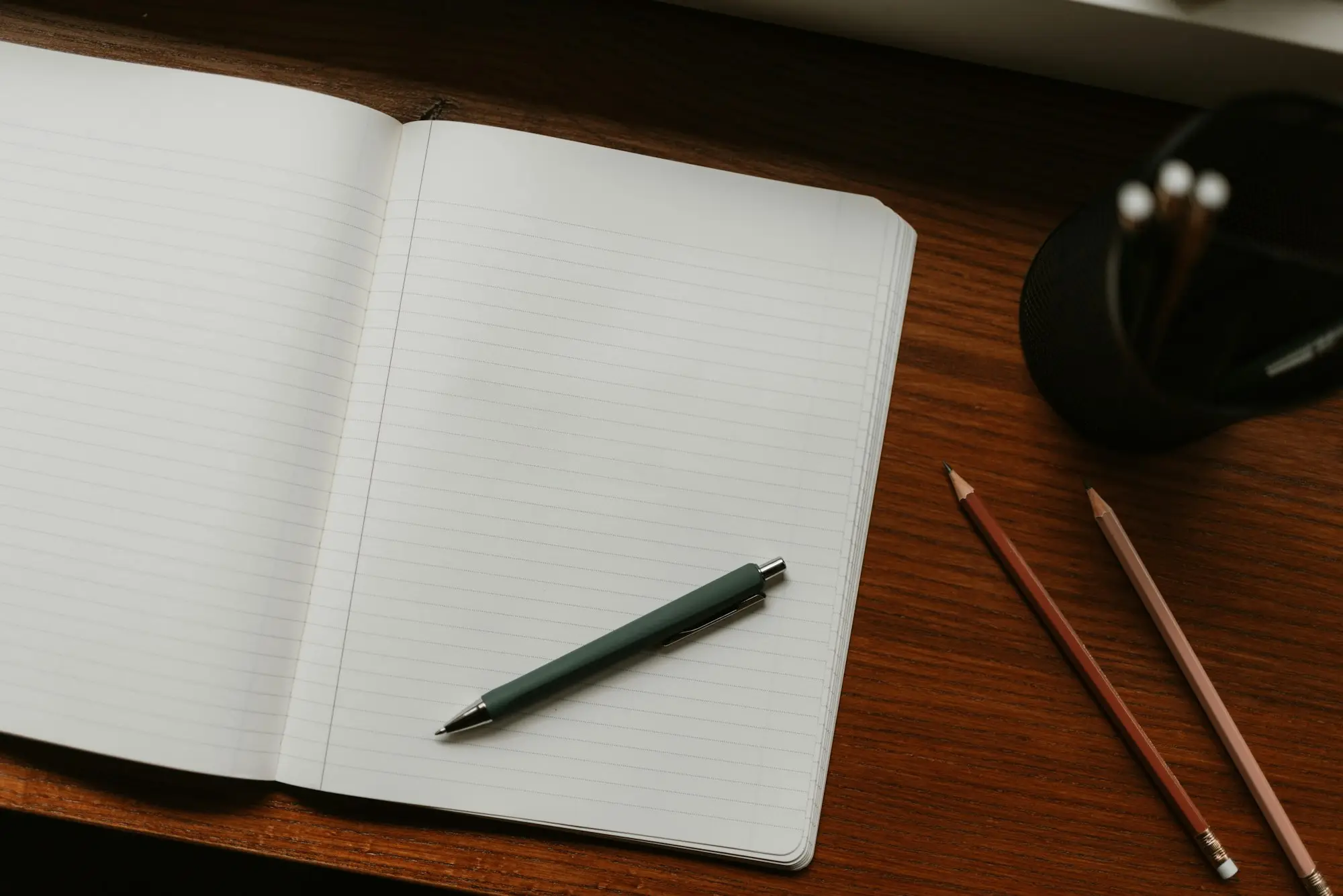Open notebook with a pen and pencils ready for planning